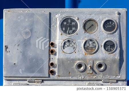 Old boat control panel with analog gauges in industrial setting Old boat control panel with analog gauges in industrial setting 138905371