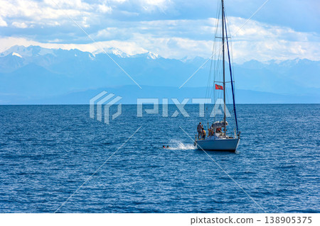 People swimming near sailboat in Kyrgyzstan waters of Issyk-Kul lake People swimming near sailboat in Kyrgyzstan waters of Issyk-Kul lake 138905375