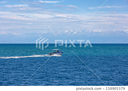 Boat sailing on tranquil water with mountains in background Boat sailing on tranquil water with mountains in background 138905379