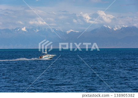 Speedboat with red national flag of Kyrgyzstan racing across waves of Issyk-Kul lake 138905382