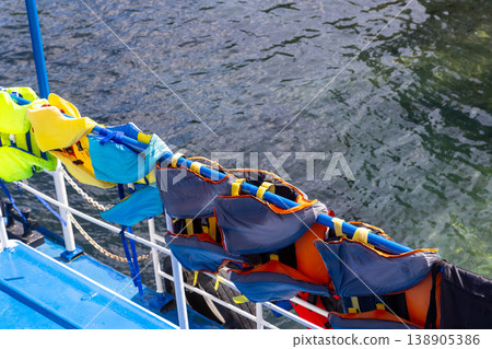 Colorful life vests hanging on boat railing with sea view Colorful life vests hanging on boat railing with sea view 138905386