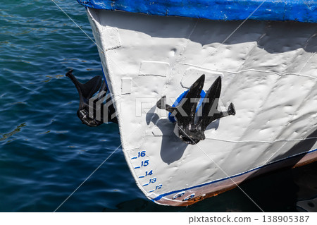 Boat bow with twin anchors and draft marks above water 138905387