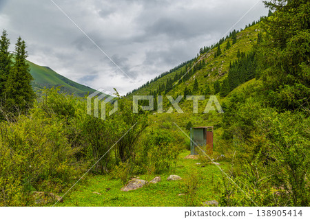 Metal toilet in serene mountain valley under cloudy sky in Kyrgyzstan Metal toilet in serene mountain valley under cloudy sky in Kyrgyzstan 138905414