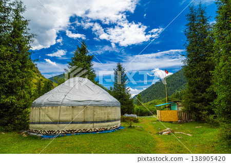 Yurt surrounded by flags, trees, and mountains in Kyrgyzstan Yurt surrounded by flags, trees, and mountains in Kyrgyzstan 138905420