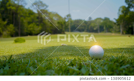 Golf ball is on a green lawn in a beautiful golf course with morning sunshine. Golf ball is on a green lawn in a beautiful golf course with morning sunshine. 138905612