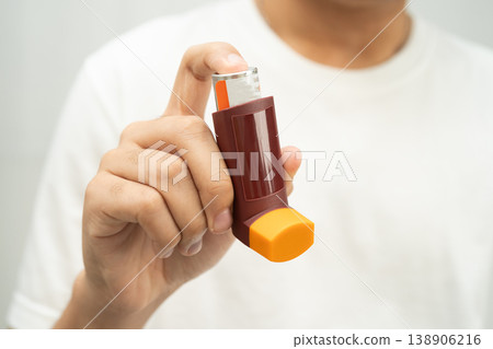 Asthma and chronic obstructive pulmonary disease COPD, Asian young man using metered dose inhaler MDI. Asthma and chronic obstructive pulmonary disease COPD, Asian young man using metered dose inhaler MDI. 138906216