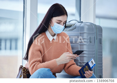 Passport, phone and covid woman travel at airport with mask, for holiday and trip. Female, check flight cancellation schedule online and with protection against coronavirus or traveling restriction 138906708