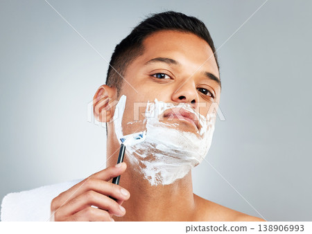 Man, razor and skincare in beauty for grooming, shave or clean hygiene against a grey studio background. Male face shaving beard with cream, cosmetics and care for healthy or fresh skin 138906993