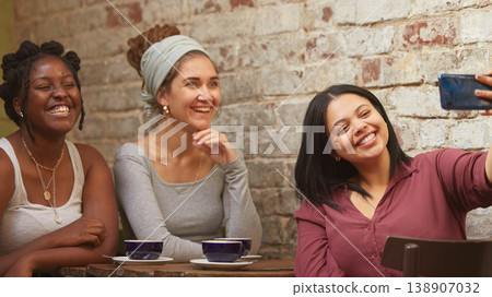 Selfie, coffee and friends at a cafe for a reunion, happy and being funny together. Coffee shop, comic and diversity with women and a photo on a phone for social media, live streaming or mobile app 138907032