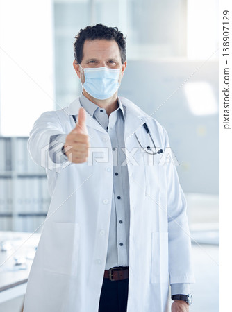 Covid, success and thumbs up with doctor in hospital for medical support, thank you and goals safety. Trust, innovation and agreement with portrait of a healthcare professional with face mask Covid, success and thumbs up with doctor in hospital for medical support, thank you and goals safety. Trust, innovation and agreement with portrait of a healthcare professional with face mask 138907129