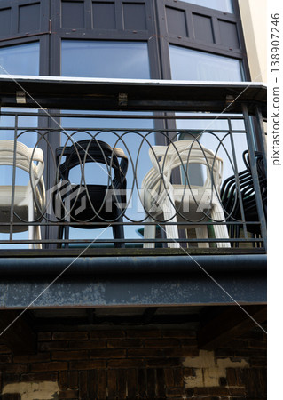 plastic chairs are folded and stand on the balcony behind the fence 138907246