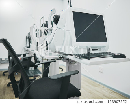 Ophthalmology machine, eye test and interior with computer for healthcare, wellness and vision in office. Optometrist consultation room, pc and furniture with digital equipment by blurred background 138907252