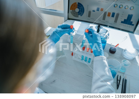 A researcher in a white lab coat and blue gloves works with test tubes, performing scientific analysis in a laboratory setting. Digital data visualizations enhance the research process 138908097