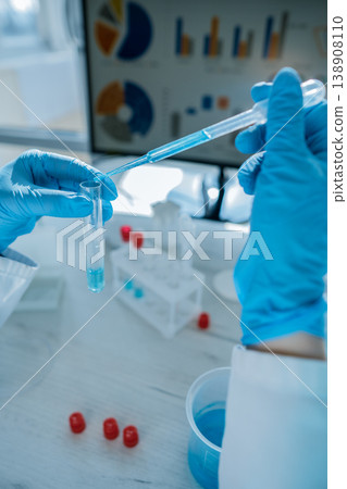 Close up hands in protective gloves performing chemical experiment with laboratory glassware, pipette. Scene highlights advanced research, innovation, scientific analysis in professional lab 138908110