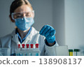 Laboratory professional wearing safety equipment analyzes test tubes with colorful liquids in bright research facility. Medical science, innovation are highlighted in this clinical laboratory setting 138908137