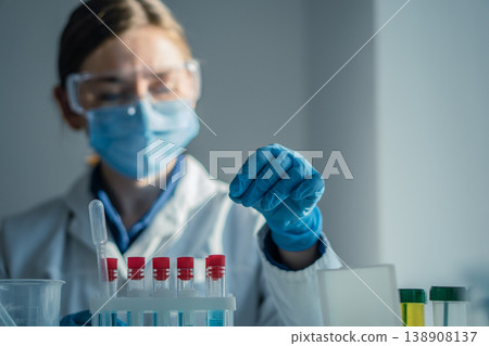 Laboratory professional wearing safety equipment analyzes test tubes with colorful liquids in bright research facility. Medical science, innovation are highlighted in this clinical laboratory setting Laboratory professional wearing safety equipment analyzes test tubes with colorful liquids in bright research facility. Medical science, innovation are highlighted in this clinical laboratory setting 138908137
