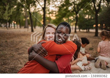 Two cheerful female teachers hugging each other in a park Two cheerful female teachers hugging each other in a park 138908362