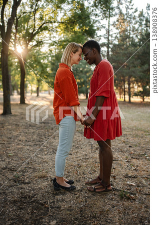 Two Young Women Holding Hands and Touching Foreheads in a Park 138908376