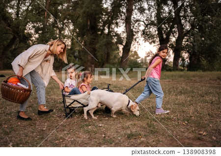 Family enjoying a leisurely walk in the park with their dog and wagon Family enjoying a leisurely walk in the park with their dog and wagon 138908398