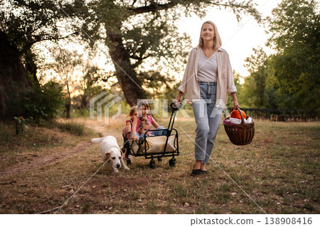 Mother Pulling Children in Wagon with Dog Following Along 138908416