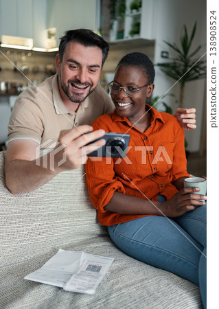 Happy couple taking selfie after paying bills using smartphone at home Happy couple taking selfie after paying bills using smartphone at home 138908524