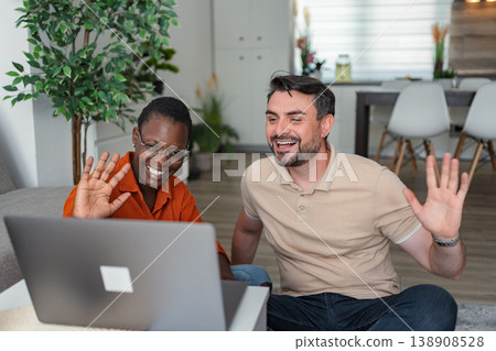 Happy Couple Video Calling and Waving at Someone on Laptop at Home Happy Couple Video Calling and Waving at Someone on Laptop at Home 138908528