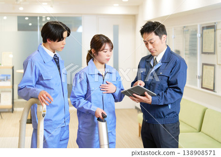 A scene from a field meeting where cleaning staff check their work details on a tablet. 138908571