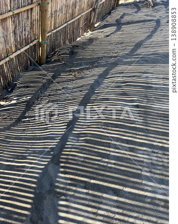 The shadow of the sand fence reflected on the sandy beach, the artistic silhouette of the bamboo sand fence installed on the coast, the silhouette of the sand fence The shadow of the sand fence reflected on the sandy beach, the artistic silhouette of the bamboo sand fence installed on the coast, the silhouette of the sand fence 138908853