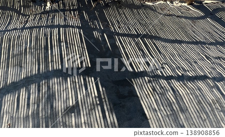 The shadow of the sand fence reflected on the sandy beach, the artistic silhouette of the bamboo sand fence installed on the coast, the silhouette of the sand fence The shadow of the sand fence reflected on the sandy beach, the artistic silhouette of the bamboo sand fence installed on the coast, the silhouette of the sand fence 138908856