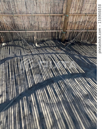 The shadow of the sand fence reflected on the sandy beach, the artistic silhouette of the bamboo sand fence installed on the coast, the silhouette of the sand fence The shadow of the sand fence reflected on the sandy beach, the artistic silhouette of the bamboo sand fence installed on the coast, the silhouette of the sand fence 138908858