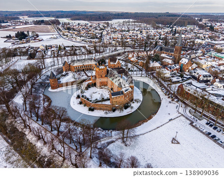 Aerial view of Huis Bergh Castle in s-Heerenberg, Netherlands, covered in fresh snow. A stunning medieval fortress with a frozen moat surrounded by a wintry town landscape and gothic church. Aerial view of Huis Bergh Castle in s-Heerenberg, Netherlands, covered in fresh snow. A stunning medieval fortress with a frozen moat surrounded by a wintry town landscape and gothic church. 138909036
