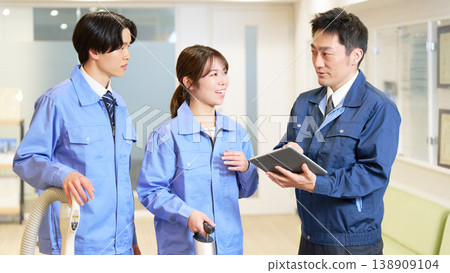 A scene from a field meeting where cleaning staff check their work details on a tablet. 138909104
