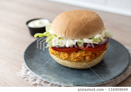 Crispy chicken burger on plate with lettuce tomato and sauce Crispy chicken burger on plate with lettuce tomato and sauce 138909694