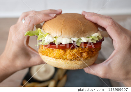 Woman holding crispy chicken burger ready to eat Woman holding crispy chicken burger ready to eat 138909697