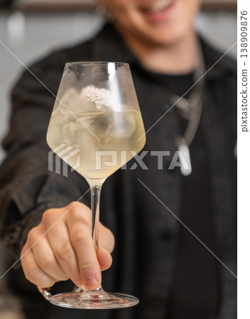 Close-up of smiling bartender holding pale floral cocktail 138909876