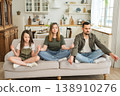 Yoga mindfulness meditation emotional wellbeing. Happy family practicing yoga at home Mother father daughter sitting in lotus pose meditating relaxing on couch Family doing breathing practice together 138910276