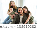 Happy family at home. Mother father two children daughters relaxing indoor. Mom dad parents baby girls kids relax playing having fun together. Family smiling laughing enjoying tender love moment 138910282