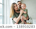 Happy family at home. Mother father holding little toddler child. Mom dad baby girl relax playing having fun together. Woman man hugging embracing baby with love care. Parent of breast feeding baby 138910283