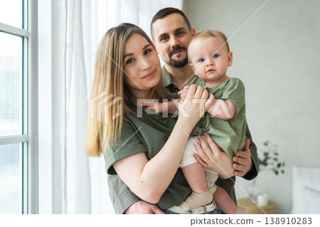 Happy family at home. Mother father holding little toddler child. Mom dad baby girl relax playing having fun together. Woman man hugging embracing baby with love care. Parent of breast feeding baby 138910283