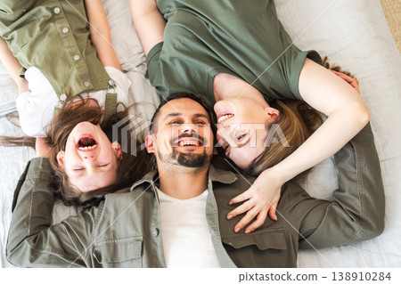 Happy family at home. Mother father children daughter relaxing in bed at home indoor. Mom dad parents kid girl relax playing hugging having fun together. Family smiling laughing enjoying tender moment 138910284
