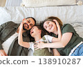 Happy family at home. Mother father children daughter relaxing in bed at home indoor. Mom dad parents kid girl relax playing hugging having fun together. Family smiling laughing enjoying tender moment 138910287