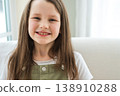 Happy girl at home. Smiling cute little brown haired Caucasian girl looking at camera. Portrait of happy female child at home. Smiling face of 10 year old girl looking at camera 138910288