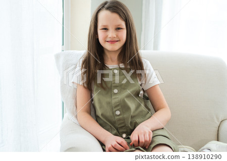 Happy girl at home. Smiling cute little brown haired Caucasian girl looking at camera. Portrait of happy female child at home. Smiling face of 10 year old girl looking at camera 138910290