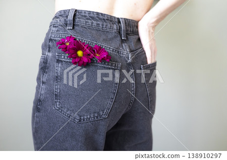 Woman with pink flower in back pocket of jeans, casual fashion detail, creative style, modern lifestyle, spring vibe. 138910297