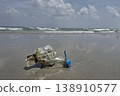 Ocean's Unwanted Guest: A weathered plastic bottle lies stranded on the sandy shore, a stark reminder of environmental pollution and the urgent need for conservation. 138910577