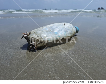 Ocean's Unwanted Guest: A weathered plastic bottle lies stranded on the sandy shore, a stark reminder of environmental pollution and the urgent need for conservation. Ocean's Unwanted Guest: A weathered plastic bottle lies stranded on the sandy shore, a stark reminder of environmental pollution and the urgent need for conservation. 138910578