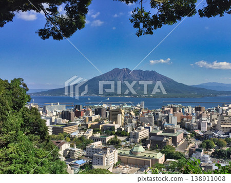 A panoramic view from a hilltop overlooking the mountains and city across the sea. 138911008
