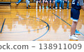 Basketball players prepare for the game in a gym during a youth sports event with fans in the background and a polished wooden floor 138911009