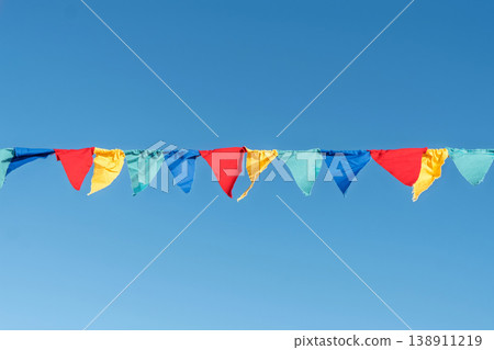 Colorful flags hanging against a clear blue sky during a celebration in a public space at daytime Colorful flags hanging against a clear blue sky during a celebration in a public space at daytime 138911219