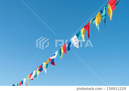 Colorful flags wave in the sky during a clear day at a cultural event with a bright blue background Colorful flags wave in the sky during a clear day at a cultural event with a bright blue background 138911220